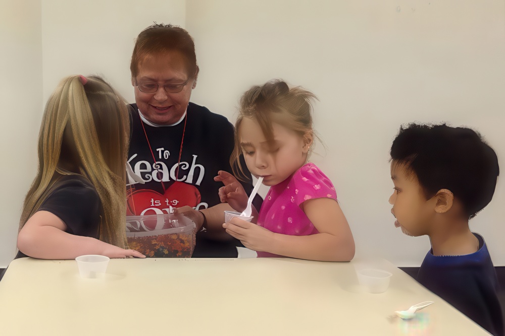 A teacher engages with young children in a fun, hands-on learning activity, fostering curiosity and interaction.