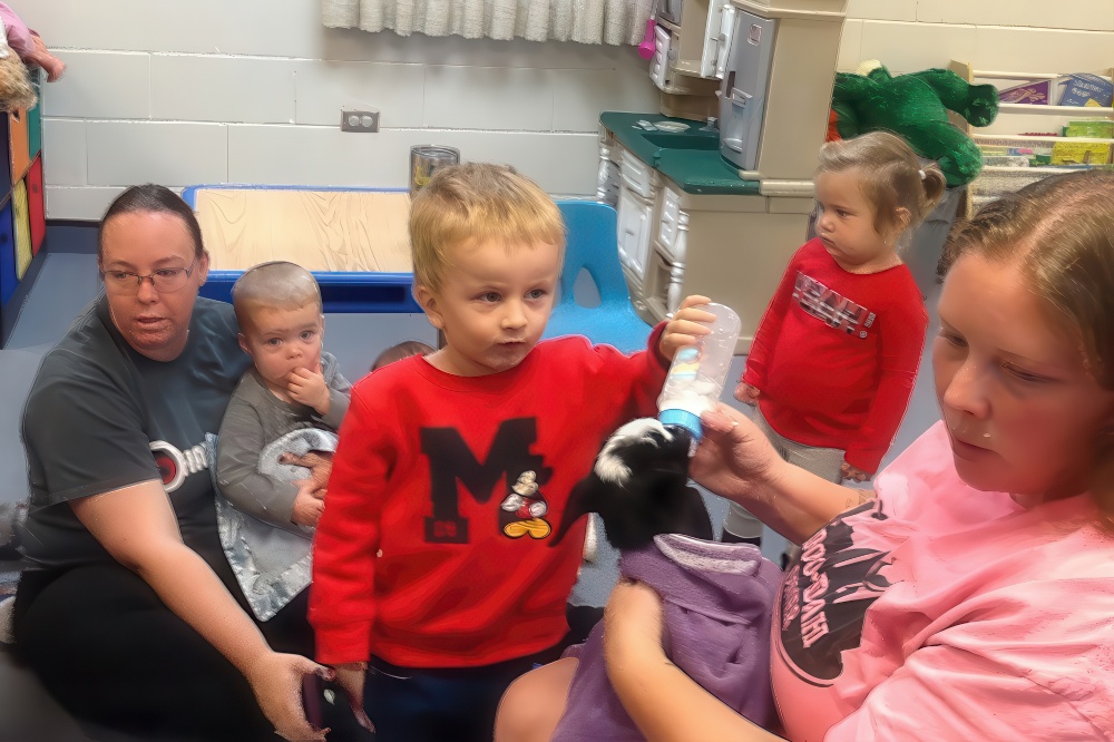 Children explore hands-on learning by bottle-feeding a baby animal, fostering care, curiosity, and development.