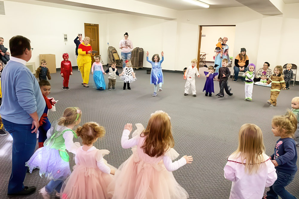 Children in colorful costumes joyfully dancing in a vibrant indoor gym designed for year-round fitness activities.