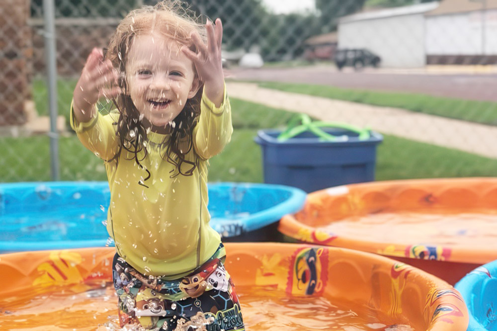 A young girl joyfully plays in a pool, enjoying daily outdoor activities that enhance her physical and mental development.