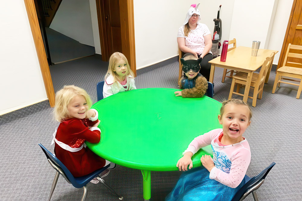 A classroom scene featuring children collaborating at a green table, emphasizing personalized learning in small groups.