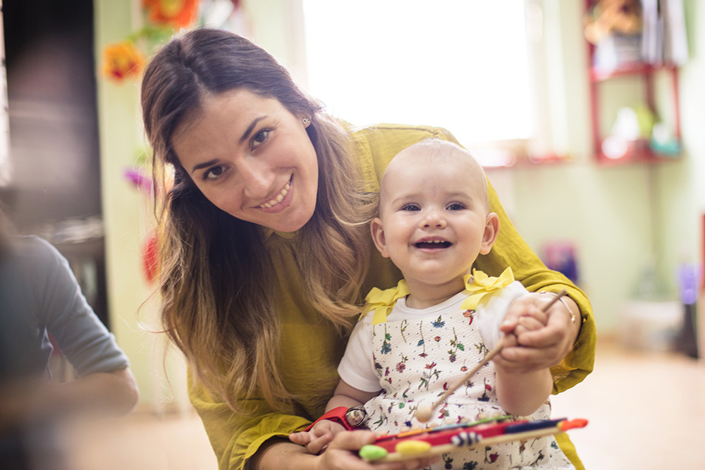 A woman smiles warmly while holding a baby, showcasing the love and guidance