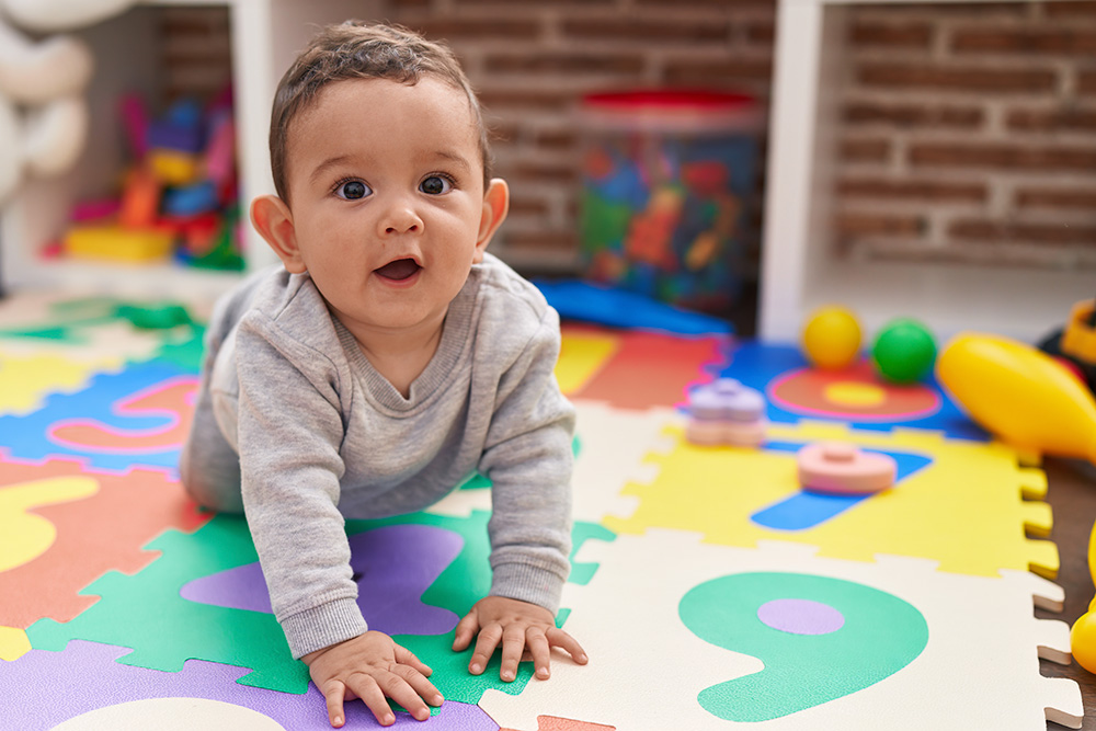 A baby crawls on a vibrant, colorful floor, emphasizing a safe and playful environment for exploration.