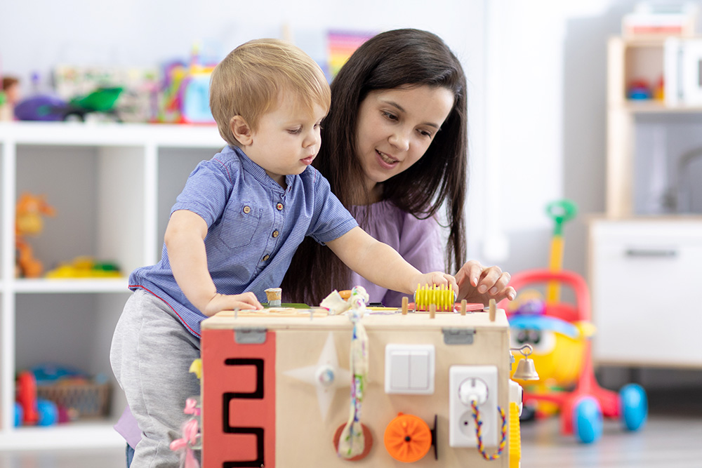 A woman and child joyfully engage with a colorful wooden toy box, fostering early learning and development skills.