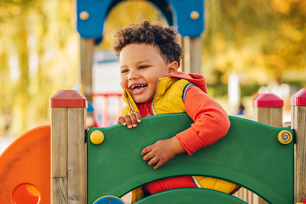 A happy boy plays on the playground, highlighting how outdoor fun boosts physical and mental growth.