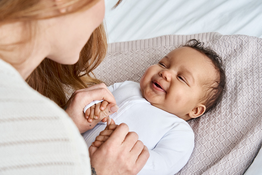 A joyful woman holds a baby, showcasing a moment of love and tenderness, symbolizing endless affection and care.