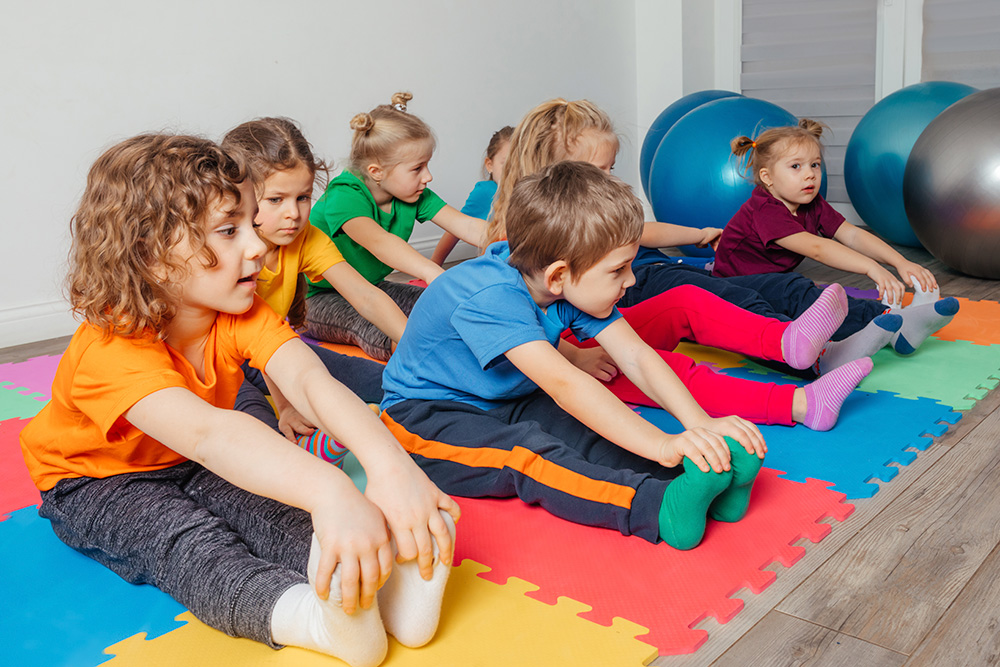 Children practicing yoga in a gym, promoting fitness and fun in a year-round indoor environment.