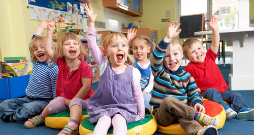 A group of children joyfully raising their hands in the air, expressing excitement and enthusiasm together.